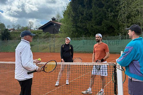 Tennisleherer erklärt mit Ball und Schläger etwas einer Gruppe vpn Übenden Gruppentraining im Tennis im Bayerischen Wald
